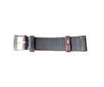 Black leather watch strap with silver buckle on a gray surface