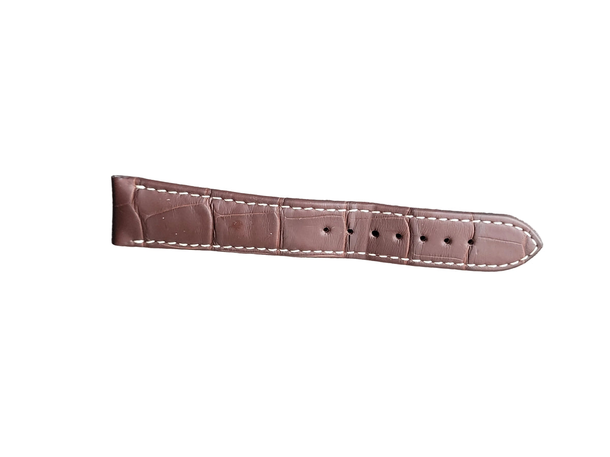 Brown leather watch strap with white stitching on a gray surface