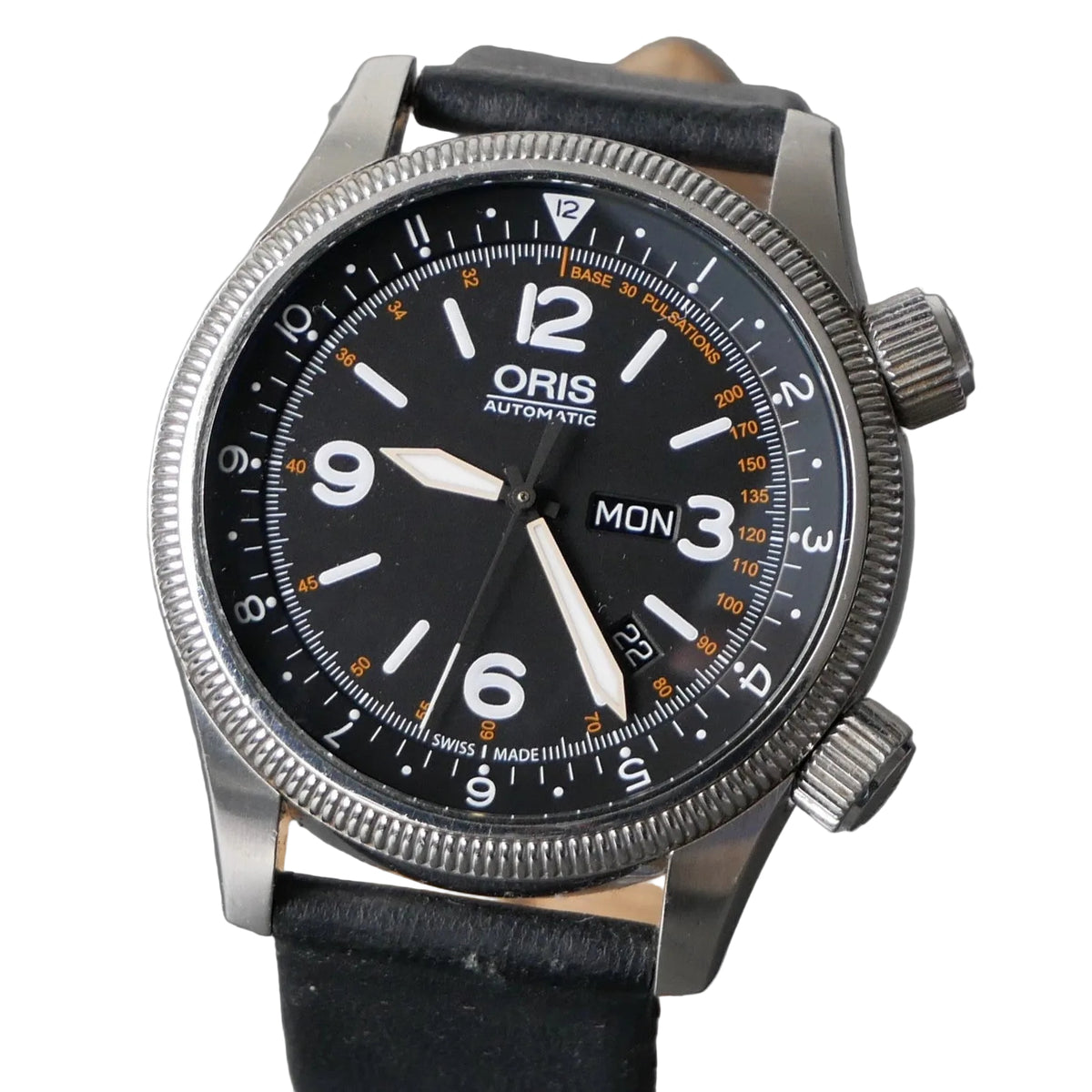 An Oris Automatic watch with a black dial, silver stainless steel case, and a black leather strap, shown close-up against a gray textured background.