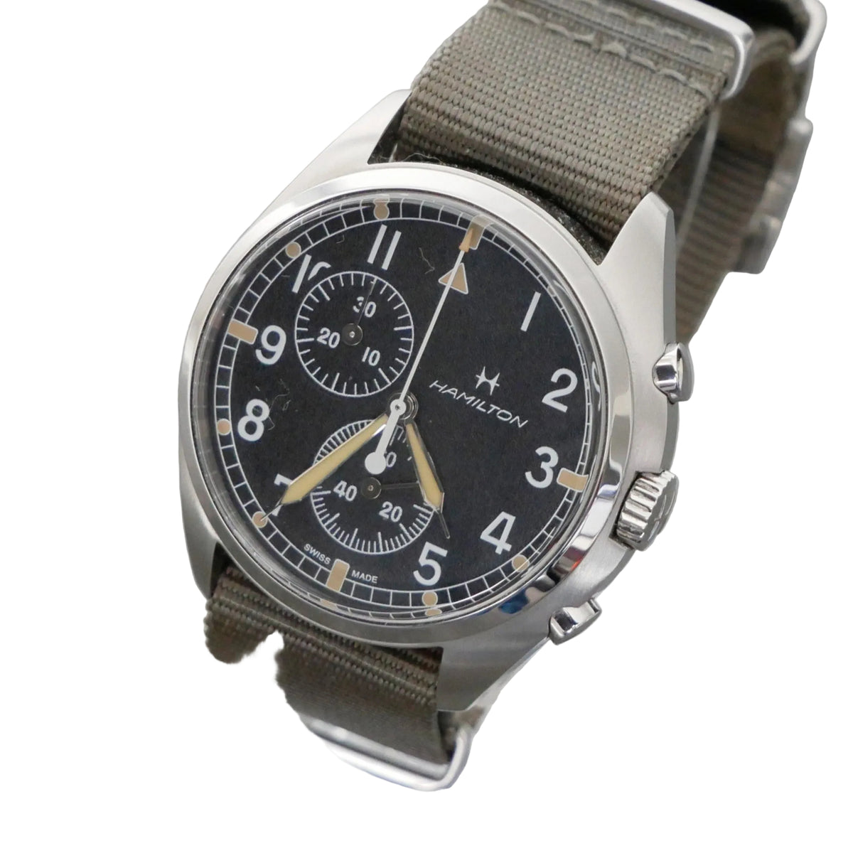 Hamilton wristwatch with a black dial, silver-tone stainless steel case, and an olive green canvas strap, displayed on a clear stand against a gray background.