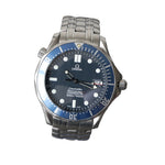 Omega Seamaster Professional diver watch with a stainless steel bracelet, featuring a blue dial, blue bezel, and silver case, displayed on a clear stand against a gray background.