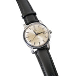 Vintage watch with black leather strap on a gray background