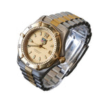 Two-tone watch with gold and silver band on a clear stand against a dark background